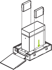Line drawing showing accessory boxes pieces being placed in the slots in the bottom tray of the DGX Station shipping carton.